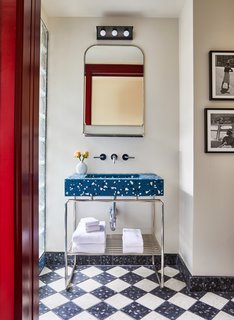 The walls and flooring are covered in terrazzo, which either appears a single shade of blue, red, or green, or in a black-and-white checkered pattern. 