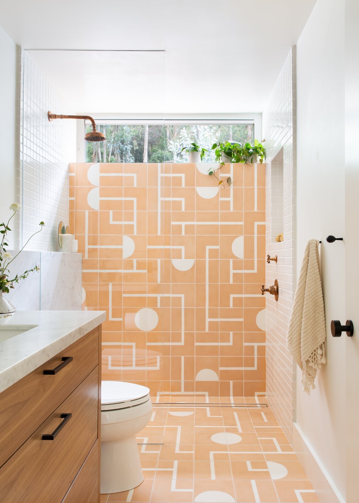 A geometric, peach-colored tile in the master bathroom adds a joyful jolt to the home. The walnut cabinetry is an ode to the home's mid-century roots.  