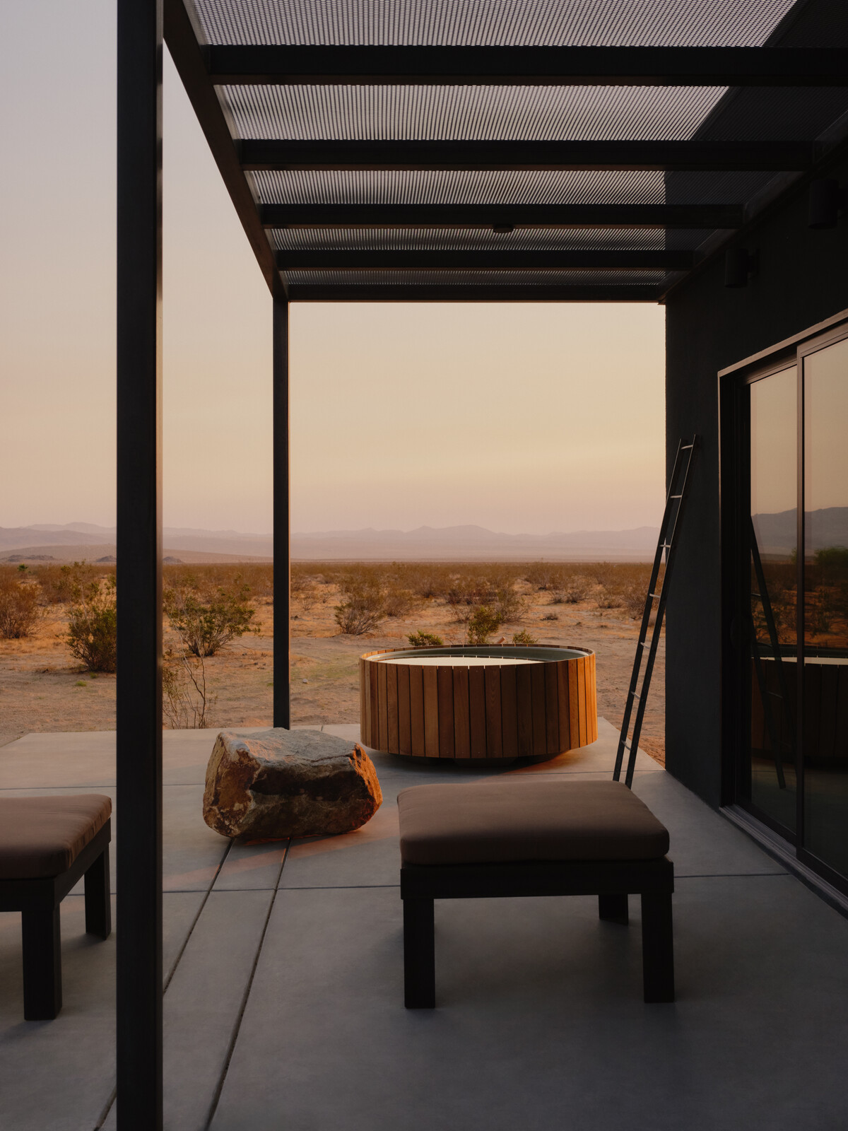 A cedar-planked hot tub looks out on to the open desert.