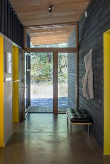 The doorways, painted a bright yellow, add a playful edge to the entrance hallway that doubles as the mudroom.
