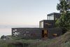 Modern home with Exterior, House Building Type, Green Roof Material, and Wood Siding Material. As they follow the slope, each volume shifts slightly to capture different frames of the surrounding water and mountains. Large sliding glass doors provide access to both these expansive views and to green roof patios. Photo 2 of Bailer Hill
