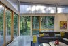 Modern home with Living Room, Wall Lighting, Concrete Floor, Coffee Tables, Sectional, Ribbon Fireplace, End Tables, Track Lighting, Sofa, Ceiling Lighting, and Wood Burning Fireplace. In the main house, large windows allow the forest to enter the living space, an effect opposite from its exterior presence. Photo 4 of Whidbey Artists' Retreat