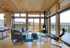 Modern home with Living Room, Wood Burning Fireplace, Ceiling Lighting, Chair, Ottomans, Coffee Tables, Light Hardwood Floor, Sofa, and Corner Fireplace. The cozy, birch plywood lined interior lets in views in all weather. The simple built-in ladder leads to a discreet hatch that opens for rooftop access. Photo 8 of Tower House