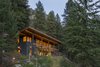 Modern home with Exterior, Shed RoofLine, Metal Siding Material, and House Building Type. Warm light emitted through the expansive windows lets the home glow warmly against the mountain and forested setting. Photo of Chechaquo