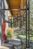 Modern home with Outdoor, Flowers, Trees, Hardscapes, Shrubs, Concrete Patio, Porch, Deck, Front Yard, Grass, Metal Fences, Wall, Walkways, and Vertical Fences, Wall. The steel-and-glulam support system forms the covered corridor of the loggia. Photo 2 of Chechaquo