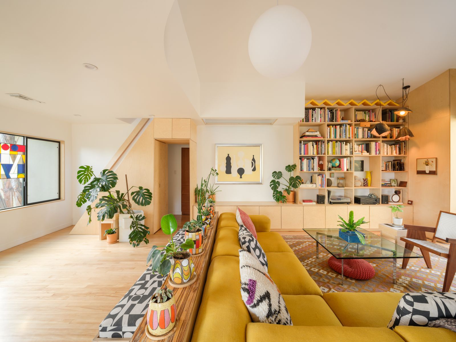 Ceramic pendants by Courtney Duncan and a yellow sculpture by Antonio join a Hay sectional in the living room. Antonio crafted the stained glass panel at left.