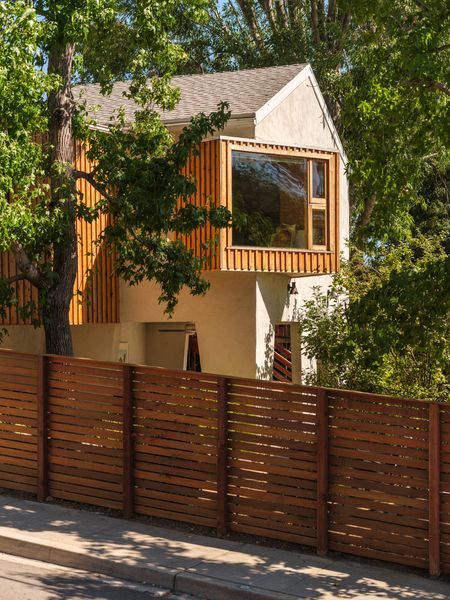 Clad in wood, a window seat cantilevers off the new primary suite and creates a covered patio below it.