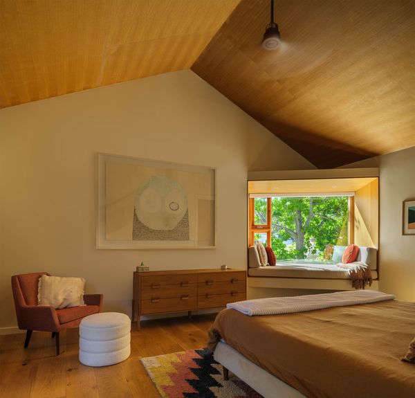 The wood ceiling and the window seat brings a treehouse feel to the primary bedroom, which the homeowners envisioned as a retreat. The side