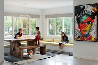 The dining room sits where the old sunroom was, and preserves the spirit of the bright and sunny space. A Spokes 2 pendant by Foscarini hangs above the dining table and bench, and graphic wall art by Venezuelan artist Raul Cardozo boldly accents the space.