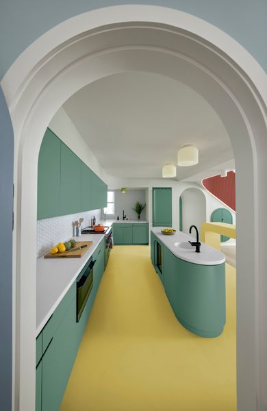 Viewed from inside the spacious new pantry, the home’s kitchen features Corian countertops in Glacier White, custom millwork and kitchen island by nottoscale, Moen Cia One-Handle High Arc faucets, paneled Sub-Zero refrigerator and wine fridge, Wolf gas range, Bosch dishwasher, Pablo Totem Flush pendant lights, and a 2