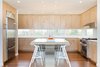 Modern home with Medium Hardwood Floor, Ceiling Lighting, Range Hood, Engineered Quartz Counter, Refrigerator, Wall Oven, Cooktops, Drop In Sink, Wood Cabinet, Stools, and Dining Room. Kitchen cabinets and horizontal slot windows frame views of the bay to the north Photo 9 of Dune Road Beach House