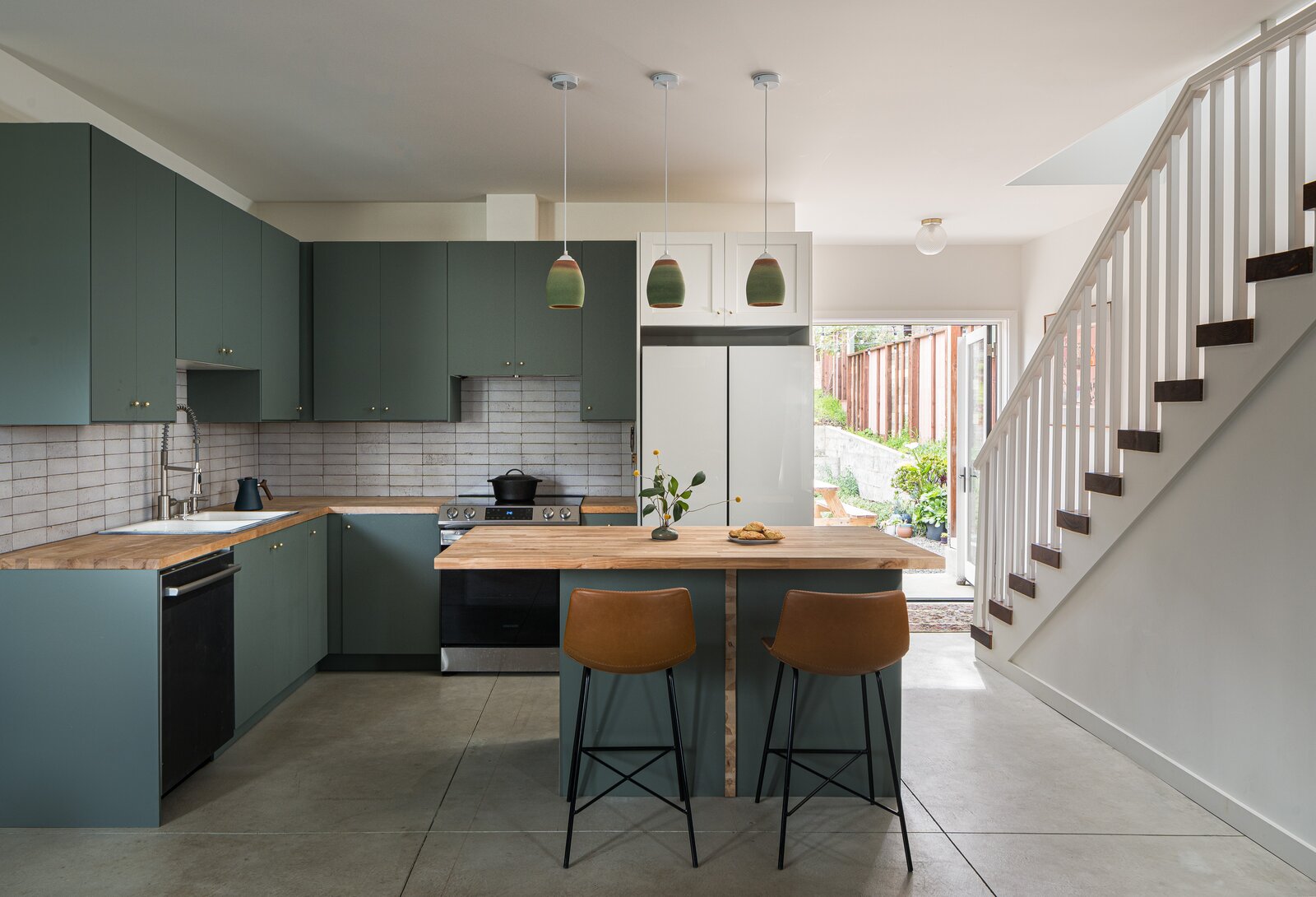The kitchen receives plenty of natural light from the French doors in back as well as from a window-lined stairway wall.