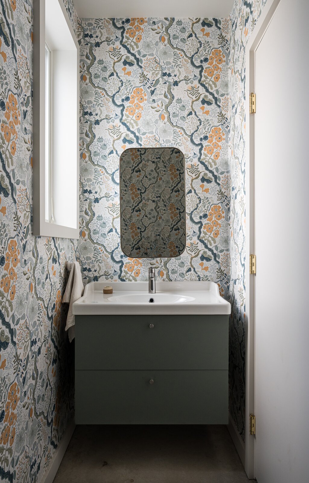 The powder room is lined with floral wallpaper from Anthropologie.