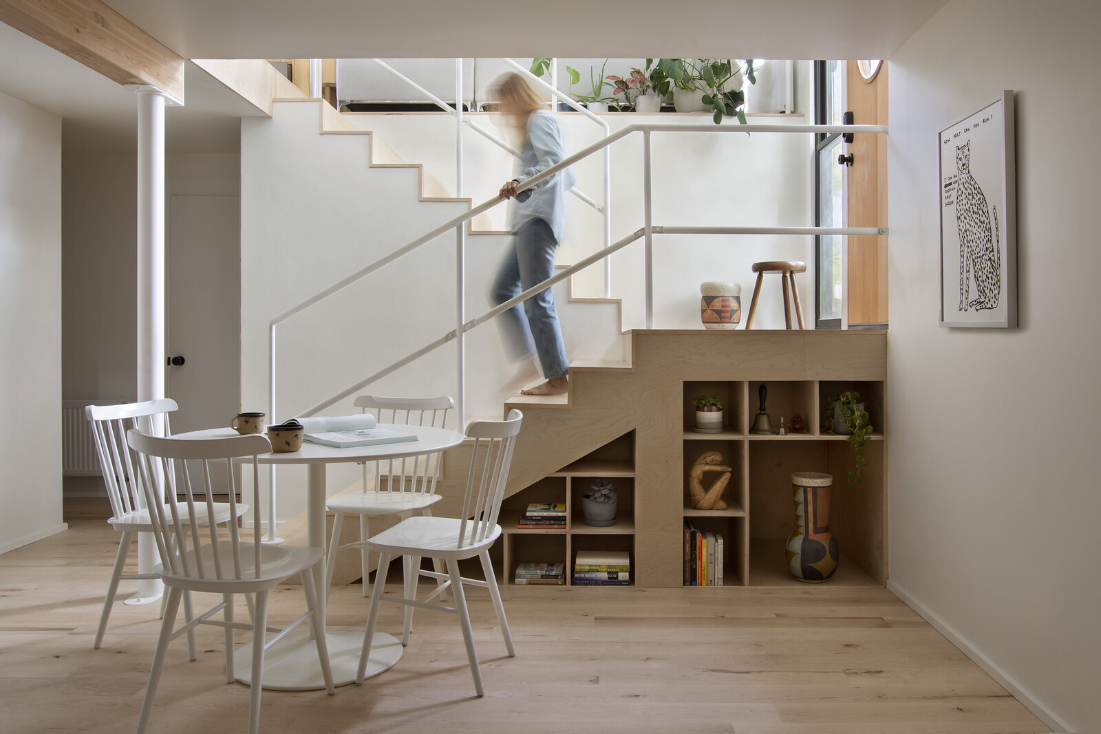 The renovated basement includes understair cabinetry designed by Allison and built/installed by Terrien Designs. The CB2 table is paired with Ton Salt chairs. The wall print is by David Shrigley.