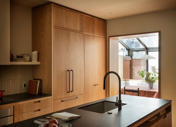 The renovated kitchen is defined by its custom oak cabinetry, as well as absolute-black granite countertops and a Heath Tile (the M144 in "oat") ceramic backsplash.