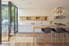 Modern home with Kitchen. The texture of this off-white tile allows light to catch at different angles, producing a graphic pattern along the tall wall behind the kitchen cabinets. The light gray of the cabinets and white countertops make for a clean and modern composition. Photo 11 of 29th Street Residence