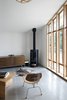 Modern home with Living Room, Chair, Console Tables, Wood Burning Fireplace, Concrete Floor, End Tables, Rug Floor, Media Cabinet, and Pendant Lighting. A wood-burning fireplace in Stable Conversion creates a sense of home. The project by SHED Architecture + Design is full of light and intended as a flexible space for guests, a home office, or a creative space. Photo 3 of Stable Conversion