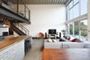 Modern home with Living Room, Sofa, Chair, and Concrete Floor. The brick found in the backsplash and island was chosen for its sympathetic materiality that is forceful enough to blend in with the native steel, while the boldly grained Zebra wood casework adds warmth and character. Photo 2 of Capitol Hill Loft