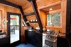 Modern home with Front Yard, Wood Patio, Porch, Deck, Small Patio, Porch, Deck, Table, Trees, Bar, Carpet Floor, Standard Layout Fireplace, Wood Burning Fireplace, Bed, Wall Lighting, Engineered Quartz Counter, Slate Floor, Drop In Sink, One Piece Toilet, and Kitchen. Kitchen Photo 5 of Homewood