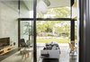 Modern home with Living Room, Pendant Lighting, Concrete Floor, End Tables, Sofa, Ottomans, Chair, Shelves, Coffee Tables, Media Cabinet, and Rug Floor. Here, you can see the spatial interplay of private and public rooms across the plan from the main bathroom through the pavilion to the landscaped setting beyond. Photo 10 of Binary House