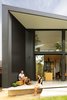 Modern home with Exterior, House Building Type, Metal Roof Material, Metal Siding Material, and Butterfly RoofLine. A peek at the northern interior-to-exterior connections via a covered terrace with its cantilevered edge and sculpted step element, doubling as seats for enjoyment of the garden. Photo 4 of Binary House
