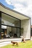 Modern home with Exterior, Metal Roof Material, Metal Siding Material, House Building Type, Butterfly RoofLine, and Concrete Siding Material. A look at the interior-to-exterior connections across a concrete terrace to the landscaped rear. Photo 8 of Binary House