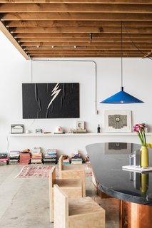 For the dining area, Breer custom-designed a table with a brass base and a marble top. A set of minimalist wood chairs and a bright blue pendant made by Simon LeComte, owner of Amsterdam Modern, complete the tableau.
