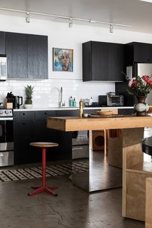 The kitchen is outfitted with black-painted cabinetry and an island Breer crafted using a vintage, stainless-steel console and a butcher-block top. "The stool is a gift from my friend Ellen LeComte at Amsterdam Mondern," Breer says. "I fell in love with the patina."