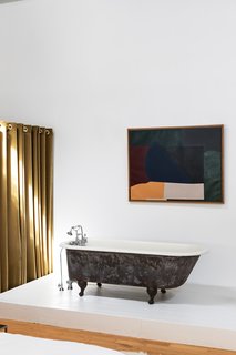 An abstract painting by modern artist Robert Breer, the designer's father, hangs above a black clawfoot tub.
