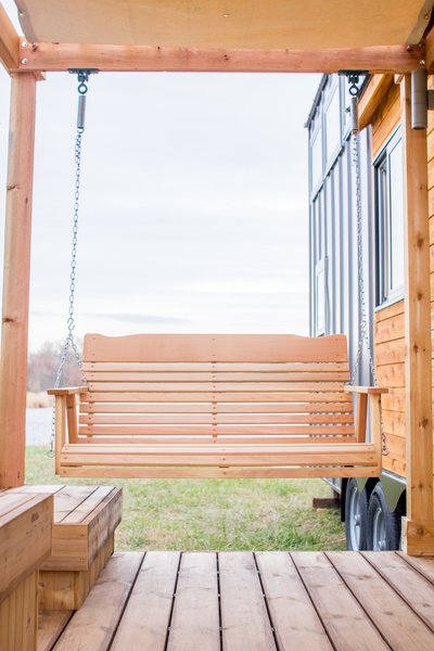 A swing hangs from a pergola on the front porch.