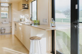 The kitchen showcases stainless-steel countertops, poplar core plywood cabinetry, and birch plywood flooring.