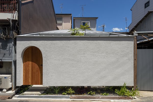 The stucco-clad tiny home is punctuated by archways, including the arched entrance, and two courtyards—one of which peeks out from beneath the cantilevered front facade.