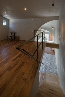 A simple metal railing and Red Acacia flooring create a minimalist aesthetic for the loft area.