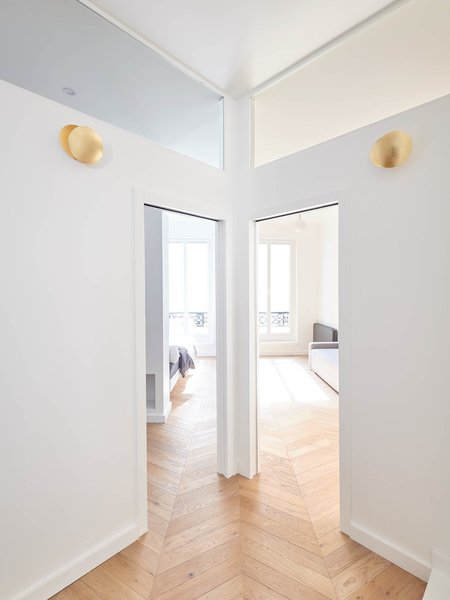 Clerestory windows allow sunlight to filter into all of the rooms in the apartment. Steel sconces with a gold finish lend a sophisticated touch to the otherwise restrained palette.