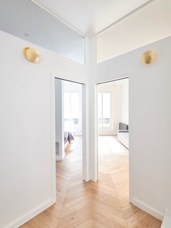 Clerestory windows allow sunlight to filter into all of the rooms in the apartment. Steel sconces with a gold finish lend a sophisticated touch to the otherwise restrained palette. 