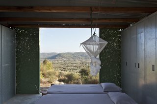 The bedroom, which also acts as a living room, features metal closets on the western elevation that provide siding as well as storage space. The green-painted metal panels on the northern elevation fold open to views of rolling hills.