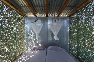 Mosquito nets suspend from the corrugated metal ceiling and provide protection from natural elements while resting or sleeping.