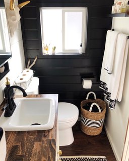 The animal skull that hangs in the bath was a wedding gift. Shaffer painted one of the walls black to add interest. "The vanity is reclaimed and we built the medicine cabinet," she says.