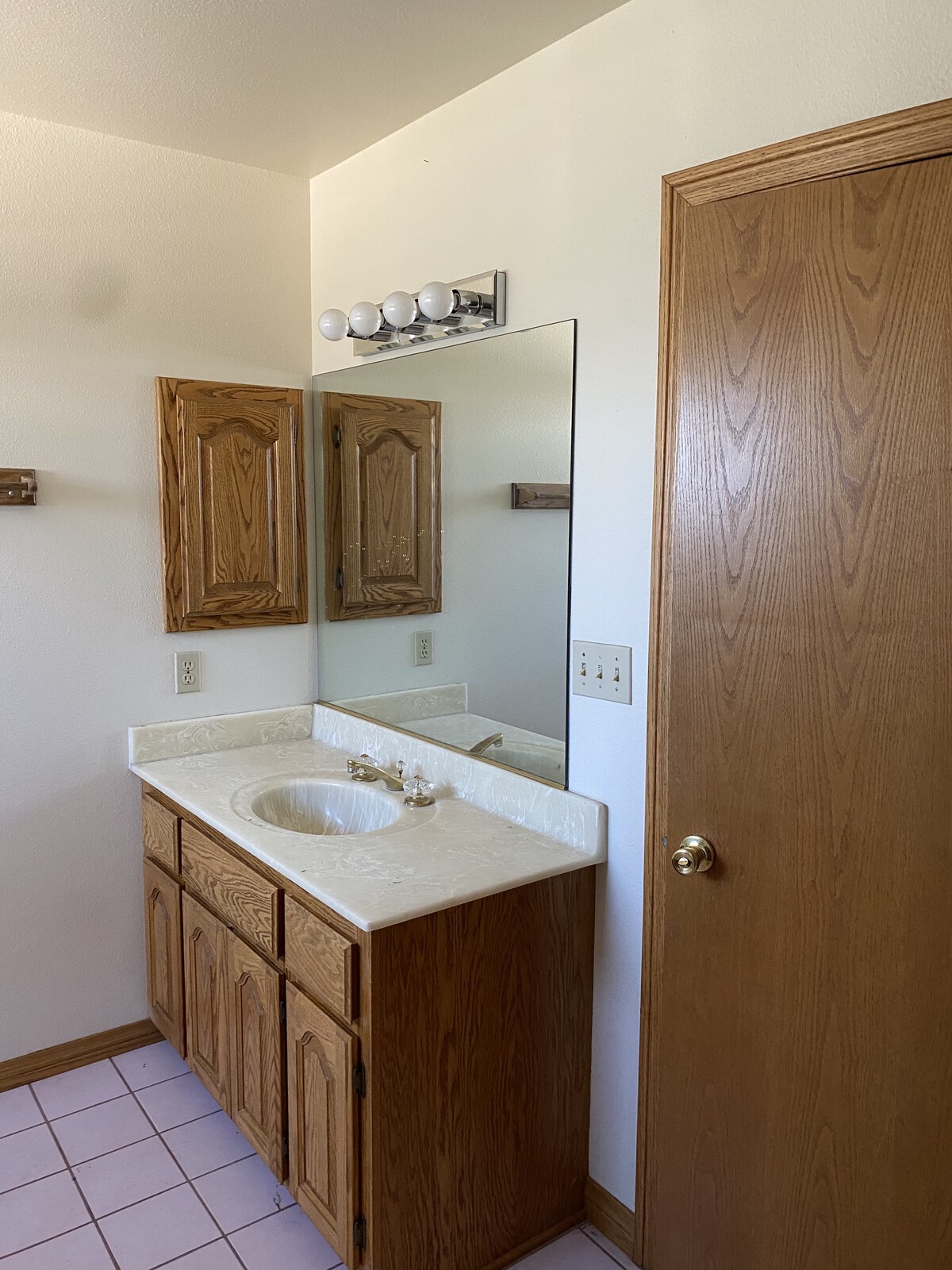 Blond wood cabinetry and dated tile flooring overtook one of the bathrooms.