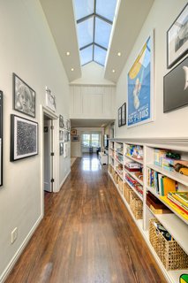 Upstairs, there are three bedrooms, customized and spacious closets, a children's bathroom, a family room, and a craft and music room overlooking the yard. The high-ceilinged hallway is brightened by natural light via a skylight which extends over the length of the passage. 