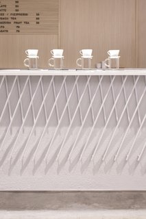 The front of the coffee bar features a decorative armor made out of angled pieces of white-painted metal that form a criss-cross pattern.
