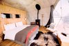 Modern home with Bedroom, Chair, Medium Hardwood Floor, Lamps, Rug Floor, Bed, Storage, Wall Lighting, and Night Stands. All the pods are equipped with organic bedding and efficient pellet wood‑burning stoves adding to the cozy interiors. Photo 4 of Whitepod Eco-Luxury Hotel