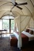 Modern home with Bedroom, Bed, Chair, Rug Floor, and Pendant Lighting. The interiors feature a modern take on colonial-expedition style and include rich teak floors and canvas walls—both of which complement dark leather furnishings and repurposed-metal details. Other highlights include freestanding copper bathtubs and four-poster beds. Photo 5 of Wild Coast Tented Lodge