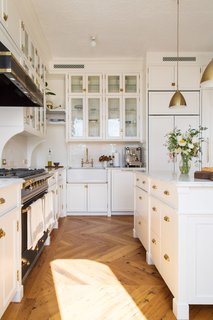 In this exquisite, classically styled black and white kitchen, gleaming white marble countertops and cabinets are juxtaposed by a dramatic, gold-trimmed black oven and range hood. Two Bestlite Pendants from Gobi enhance the gold details throughout this kitchen, a favorite among black and white kitchens.   