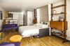 Modern home with Bedroom, Storage, Wall Lighting, Light Hardwood Floor, Chair, Bed, and Shelves. With the eclectic collection of modern furniture and vintage finds, this studio apartment makes for a unique retreat and is perfect for couples or solo travelers. Photo 8 of Unite d’Habitation