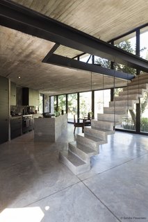 The main living area features a full-glass frontage facing the mountains and a cut stone stairway leading to the mezzanine level. 