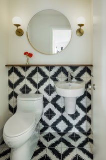 The powder room received a simple, yet stunning transformation with white paint, modern sconces from Cedar & Moss, and the addition of graphic black and white cement tile from Ann Sacks that wraps the wall.

