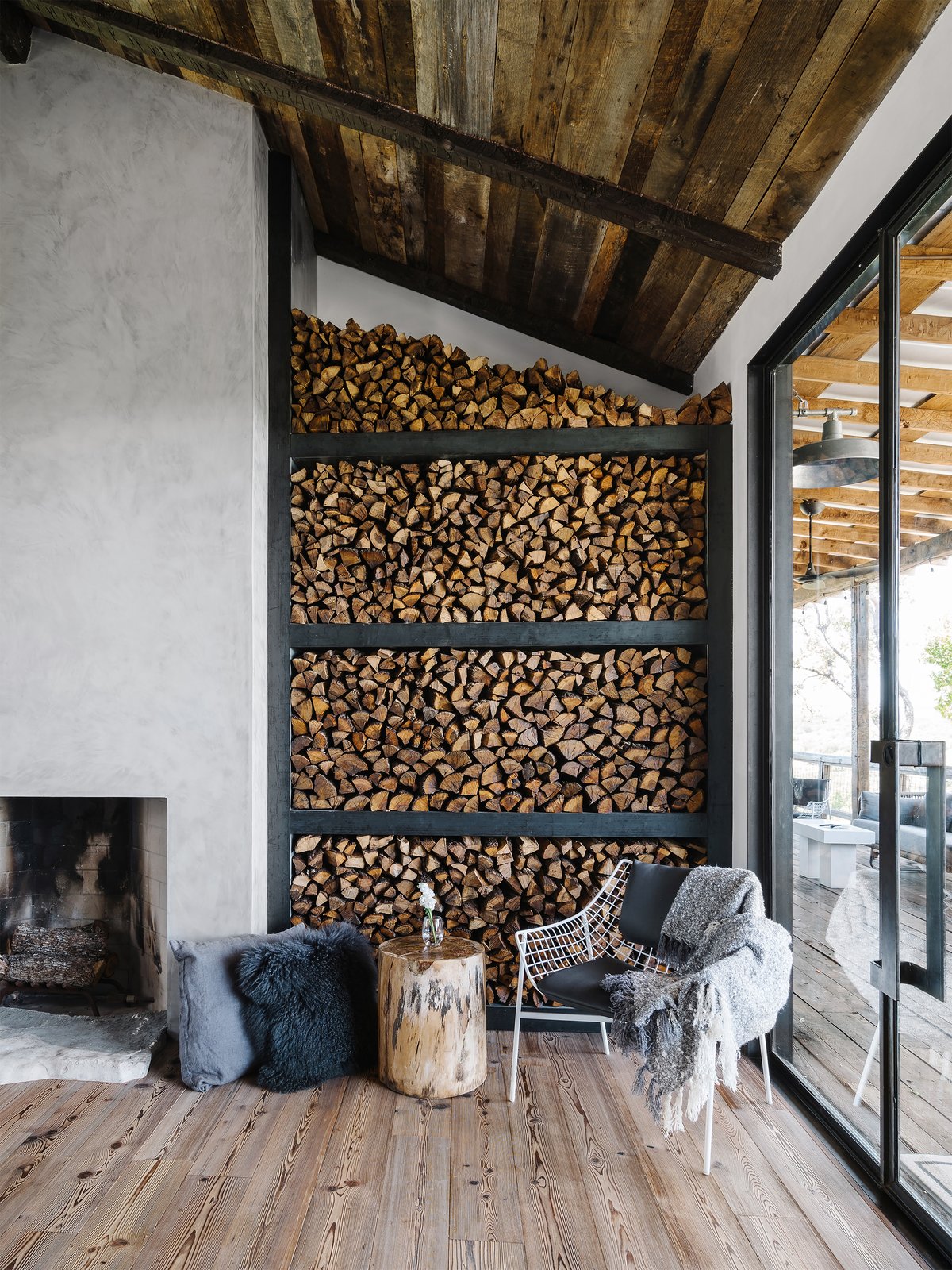 Living Room, Chair, End Tables, Wood Burning Fireplace, Medium Hardwood Floor, and Standard Layout Fireplace The existing structures were updated with a material palette that included natural aging patinas, raw steel doors and shelves, zinc countertops, and wood-paneled and beamed ceilings—juxtaposed with clean and modern smooth plaster finishes. Photo 5 of 13 in An Old Texas Ranch Becomes a Spectacular Family Haven