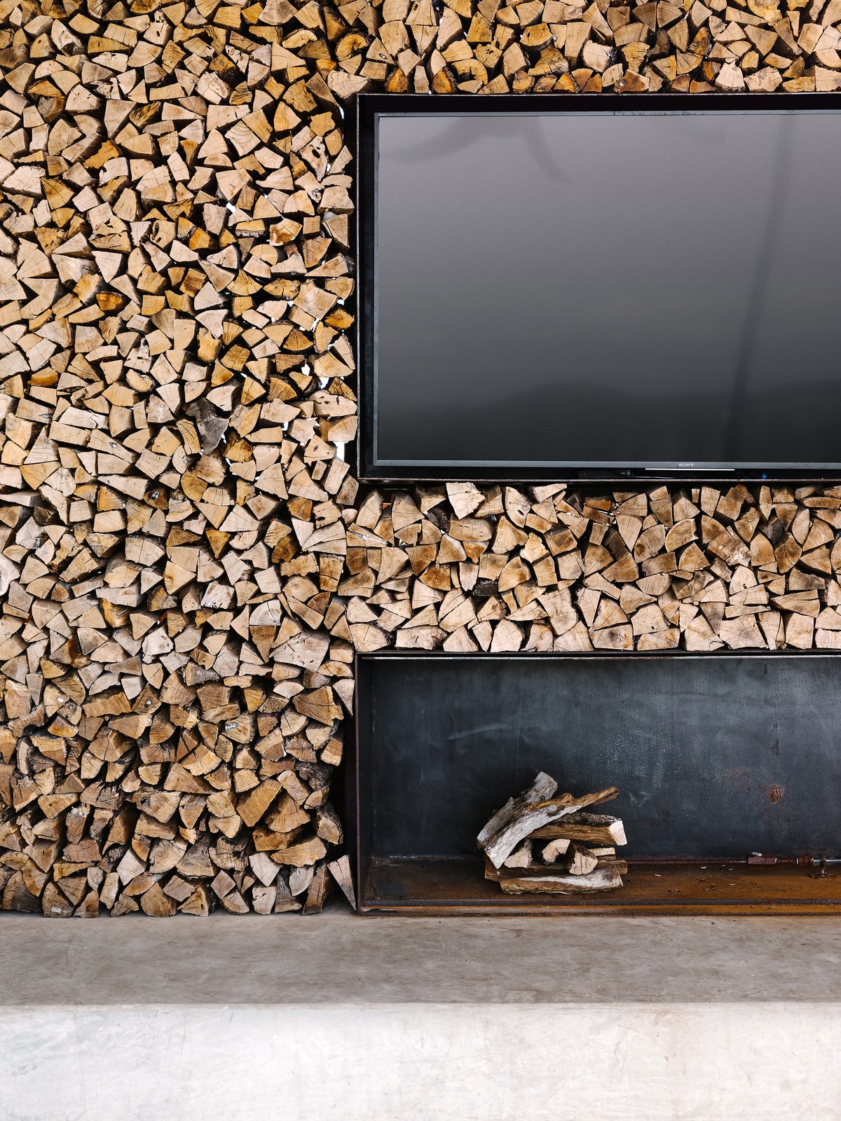 Outdoor, Large Patio, Porch, Deck, and Back Yard A wood-stacked wall adds texture. Photo 10 of 13 in An Old Texas Ranch Becomes a Spectacular Family Haven