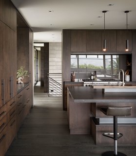 The kitchen barstools are from Ligne Roset. Vintage, Jacques Biny black enameled metal pendants from the 1960s maintain a retro feel. 